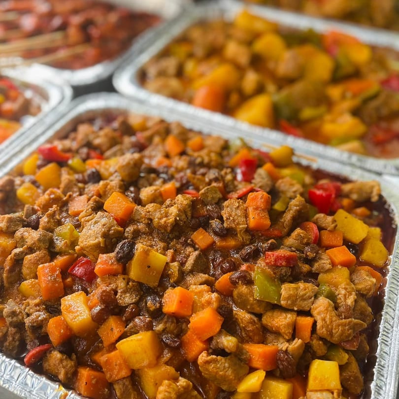 Close-up of Mang Eton's Filipino menudo, a savory stew with diced pork, vegetables, and raisins.