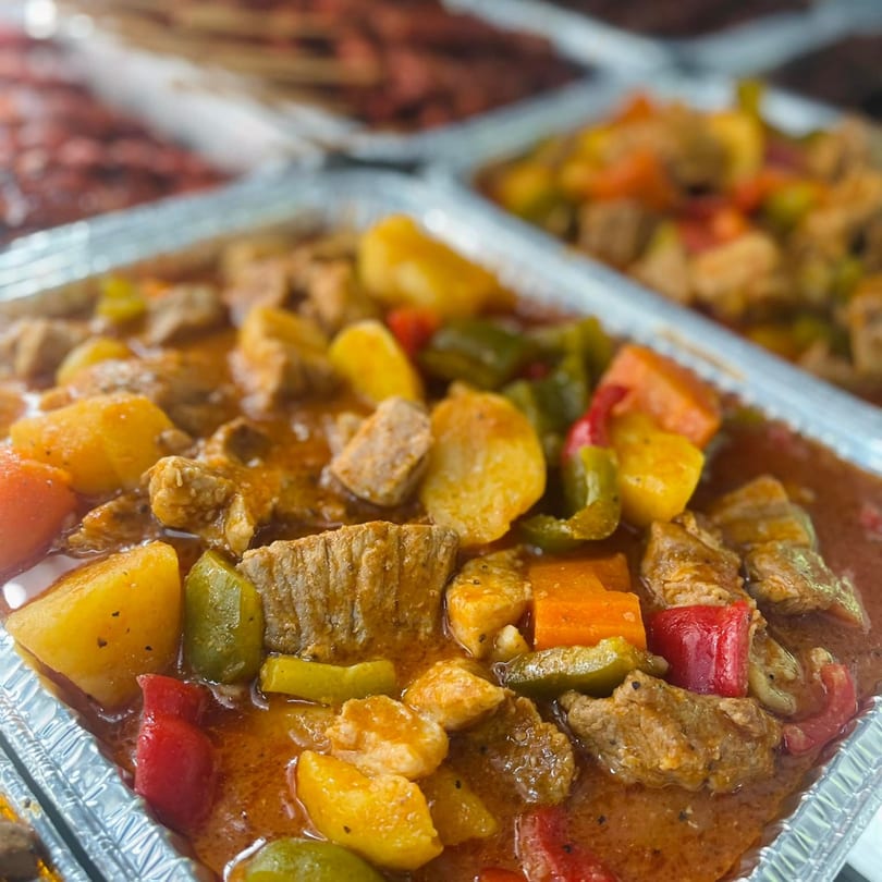 Close-up of Filipino menudo with pork, potatoes, carrots, and bell peppers in a rich sauce.
