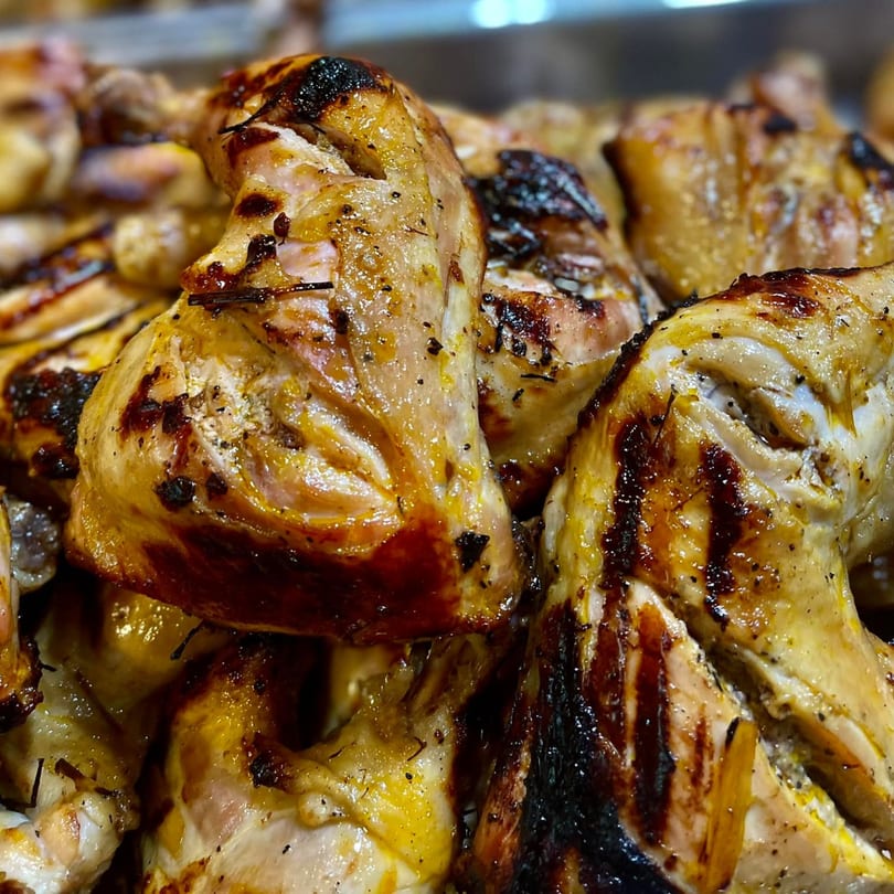 Close-up of golden-brown grilled chicken pieces with charred skin, a Filipino specialty from Mang Eton.