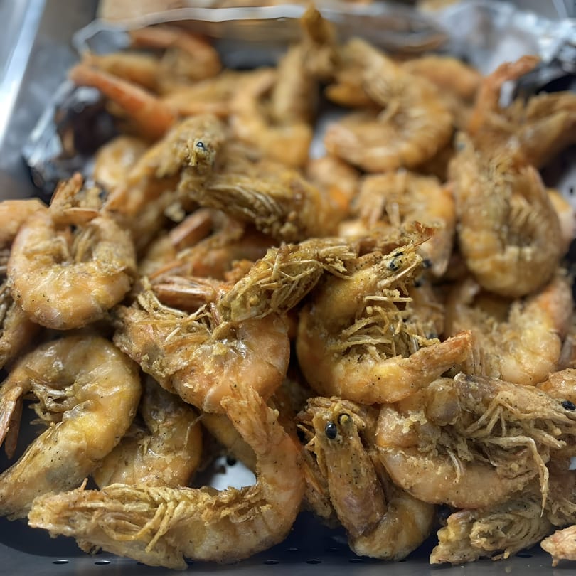 A close-up of a large pile of crispy, golden-brown fried shrimp, a Filipino delicacy.